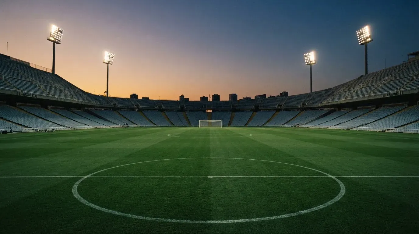 An empty football stadium with floodlight masts at dusk