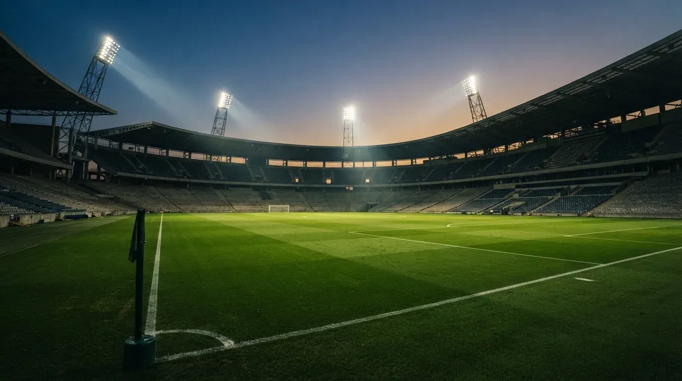 An empty football stadium with floodlight masts at dusk