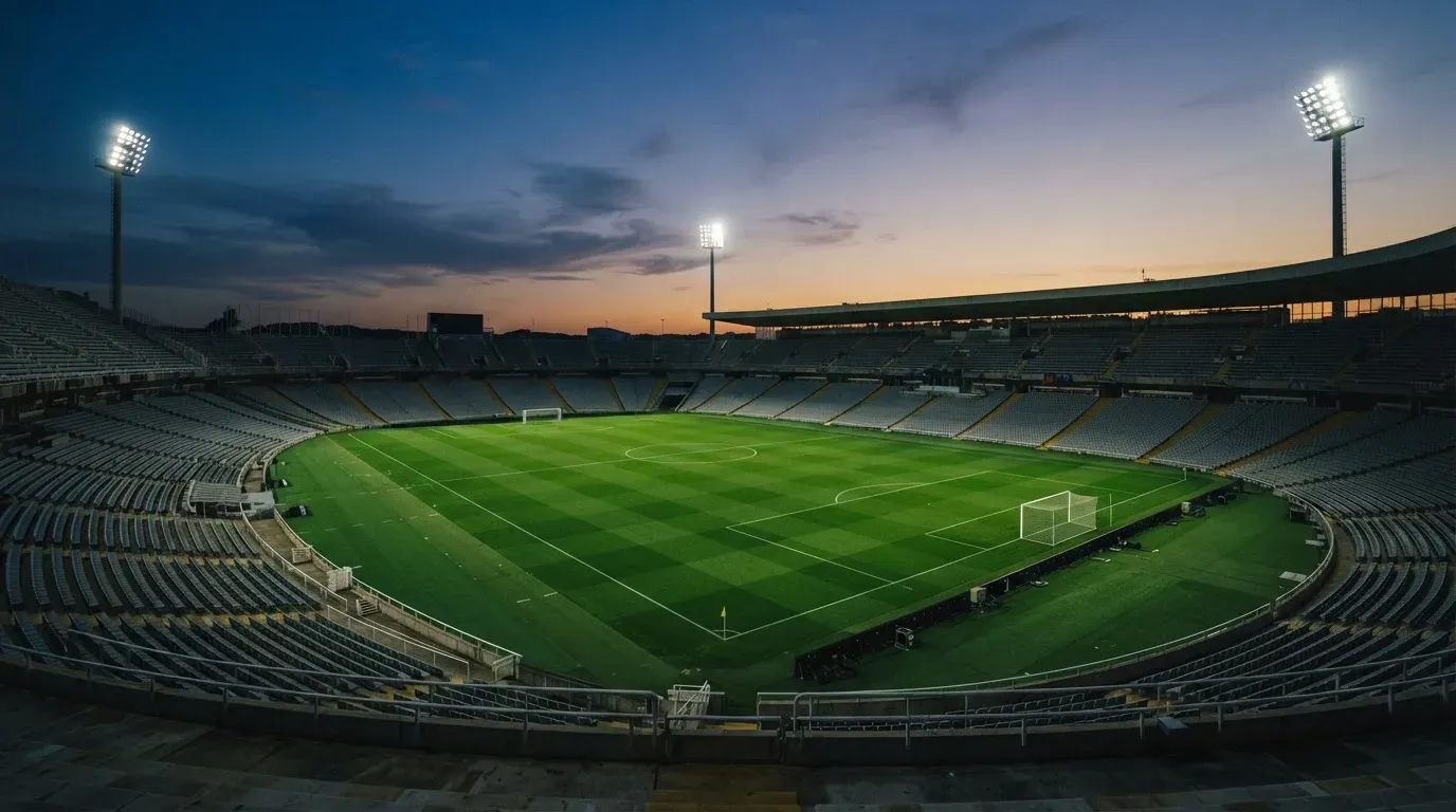 An empty football stadium with floodlight masts at dusk