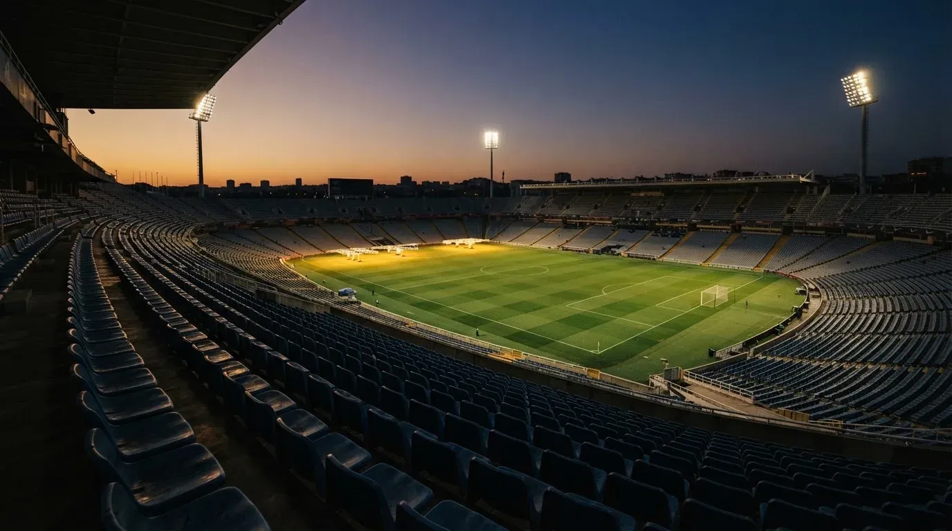 An empty football stadium with floodlight masts at dusk