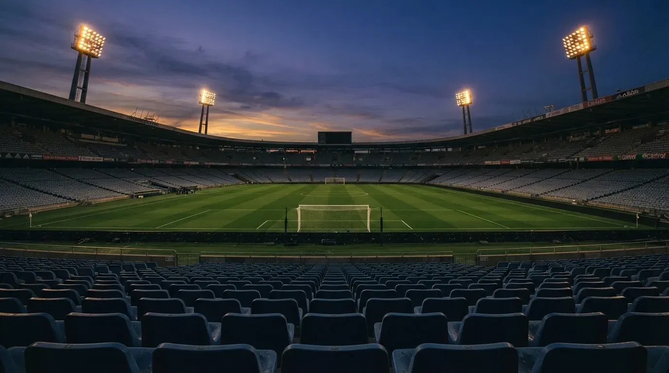 An empty football stadium with floodlight masts at dusk