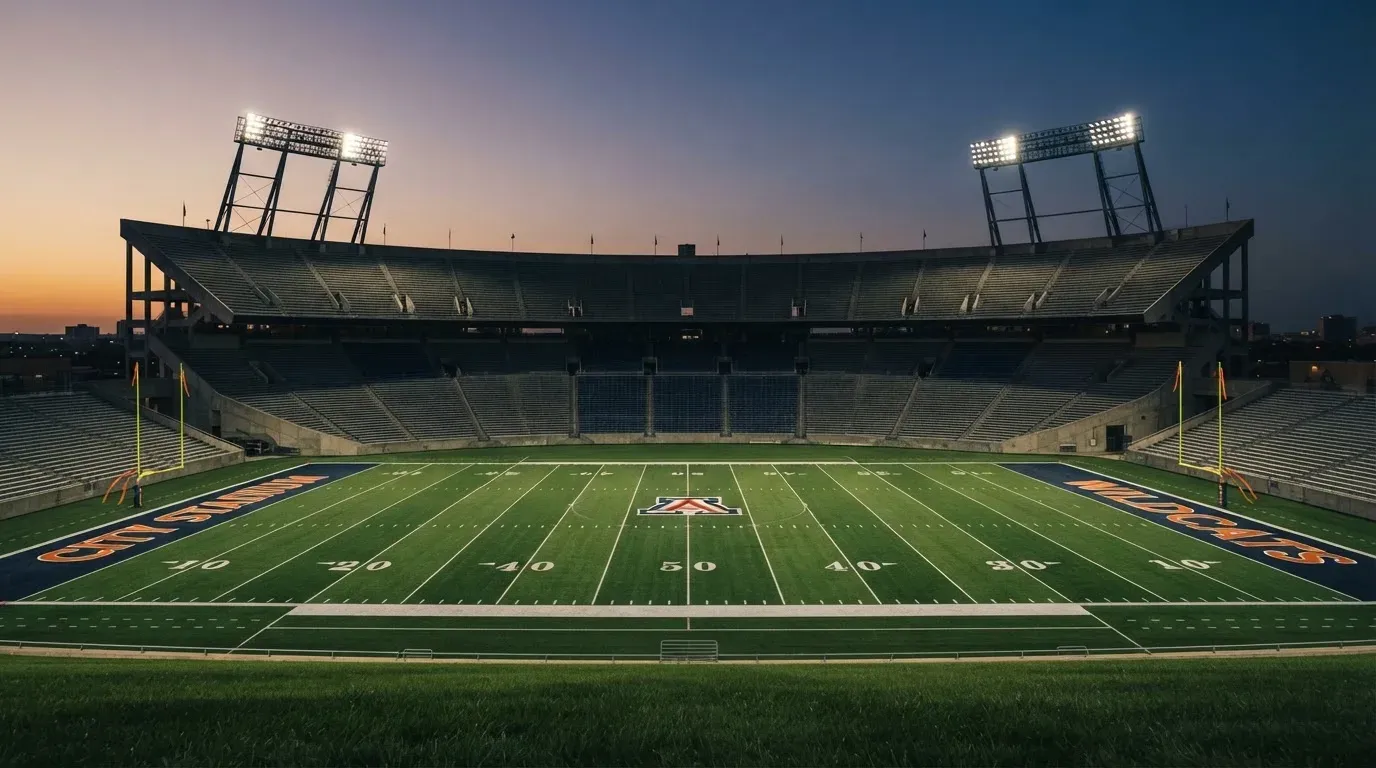 An empty football stadium with floodlight masts at dusk