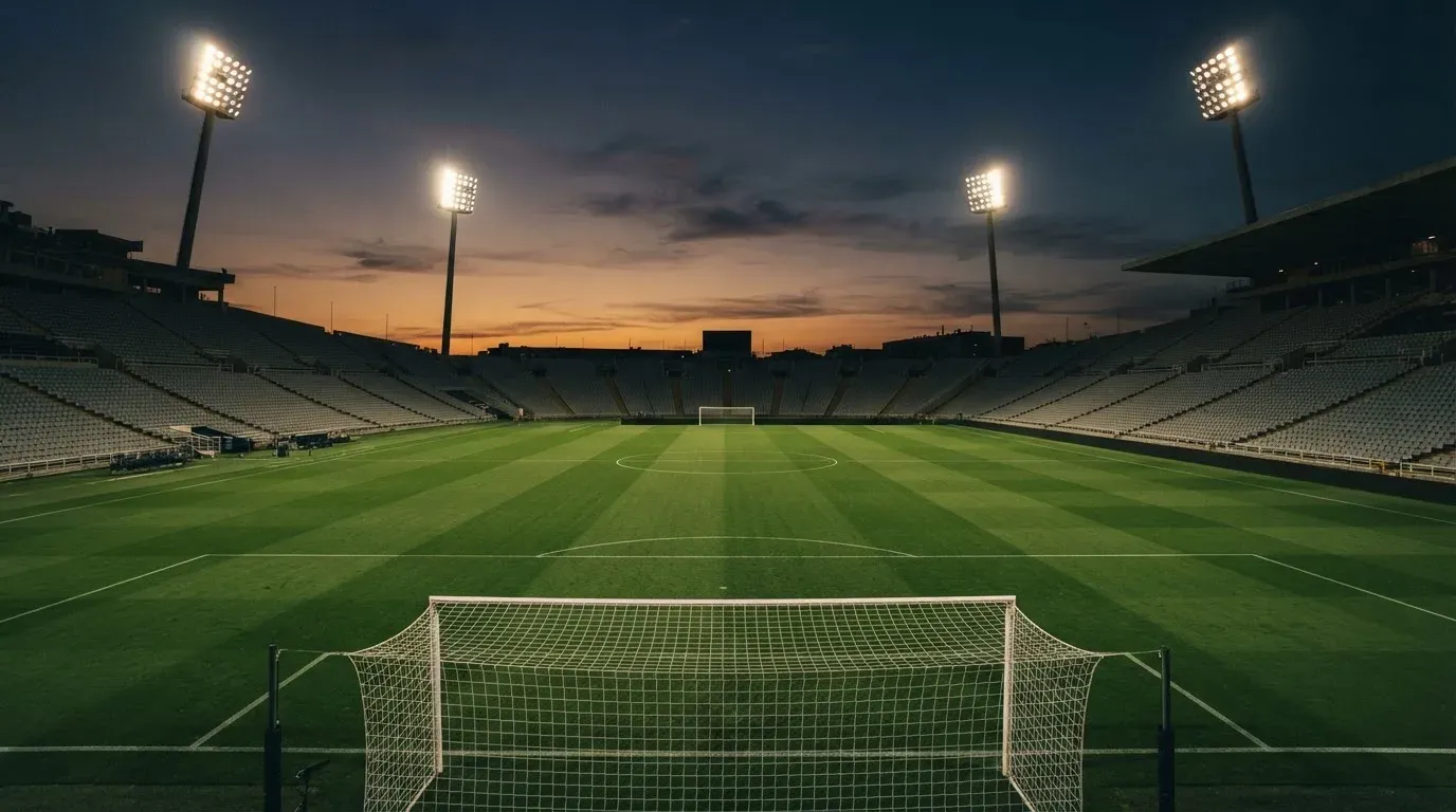 An empty football stadium with floodlight masts at dusk