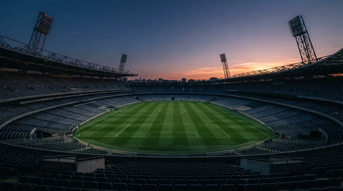 An empty football stadium with floodlight masts at dusk