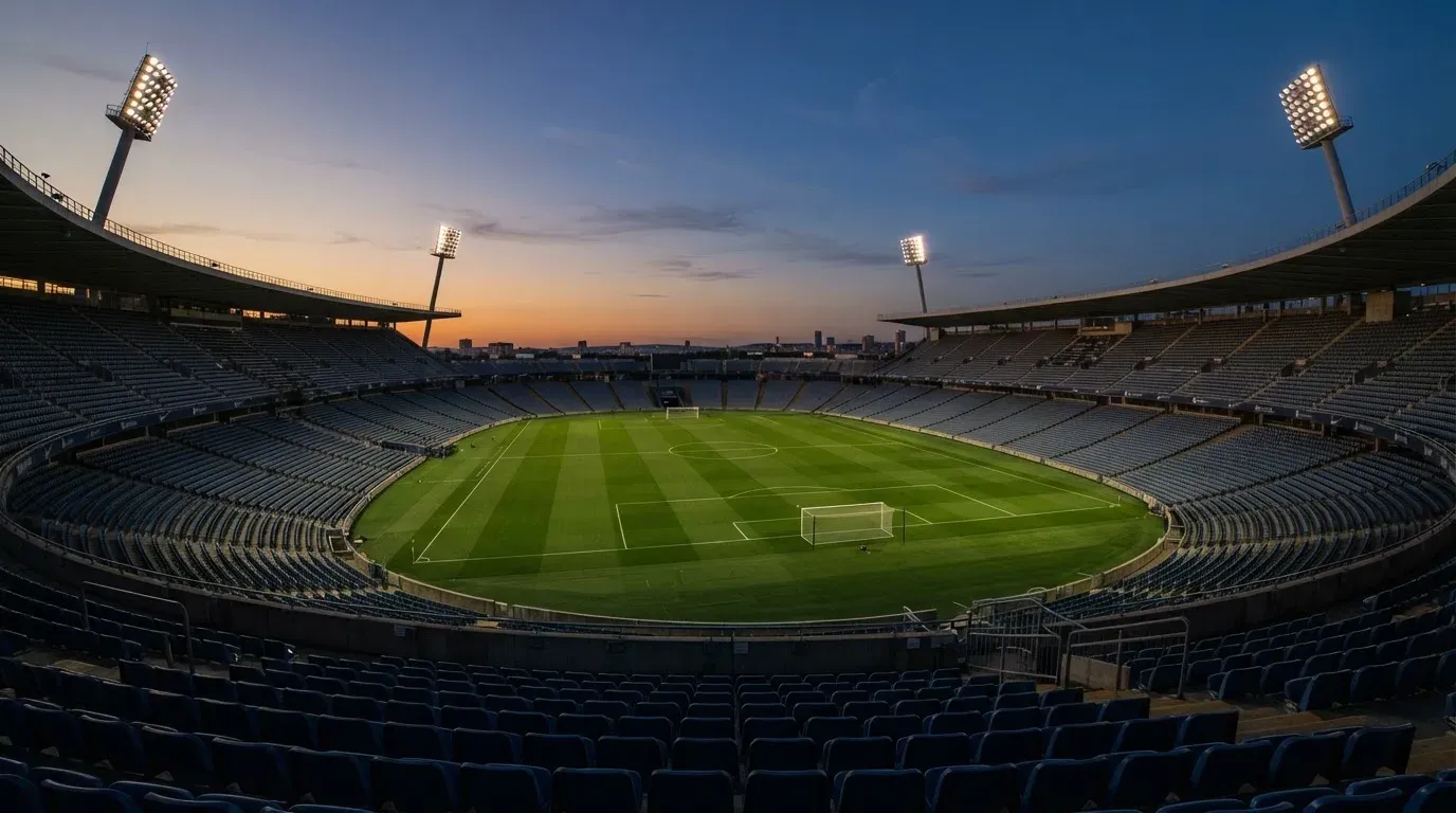An empty football stadium with floodlight masts at dusk