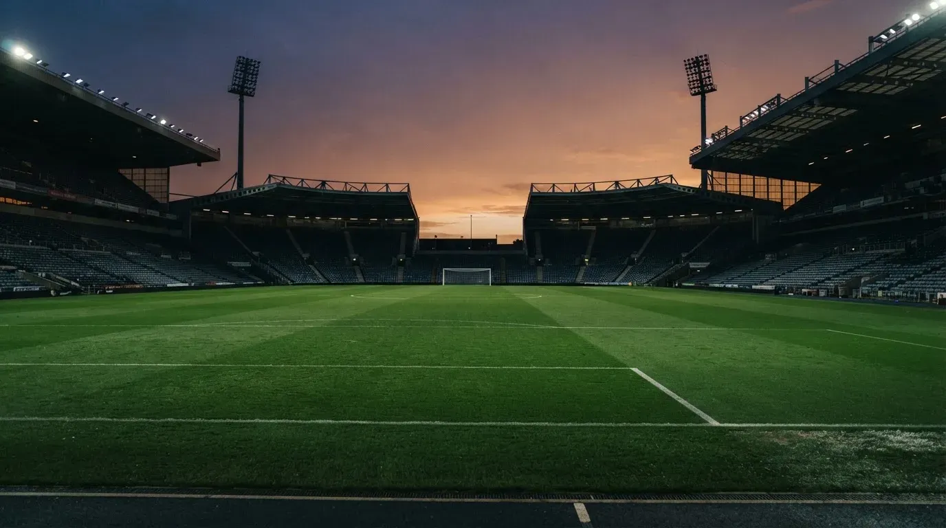 An empty football stadium with floodlight masts at dusk