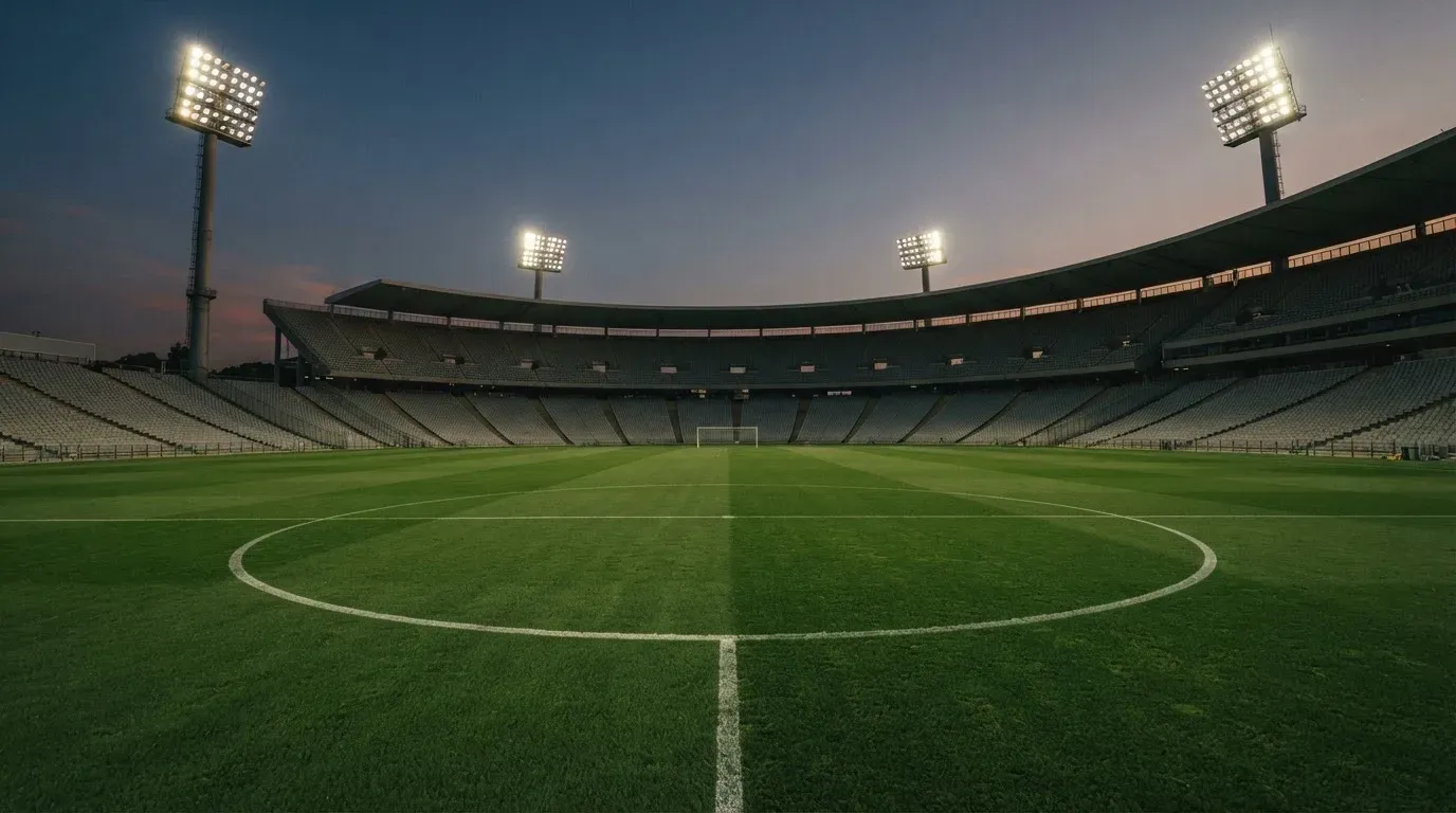 An empty football stadium with floodlight masts at dusk