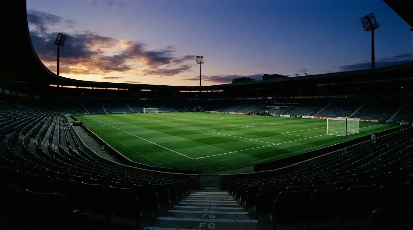 An empty football stadium with floodlight masts at dusk
