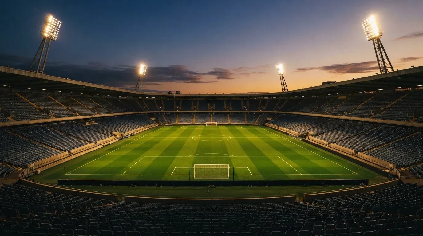 An empty football stadium with floodlight masts at dusk