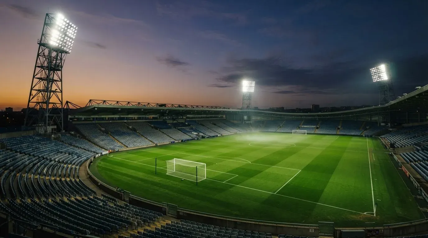 An empty football stadium with floodlight masts at dusk