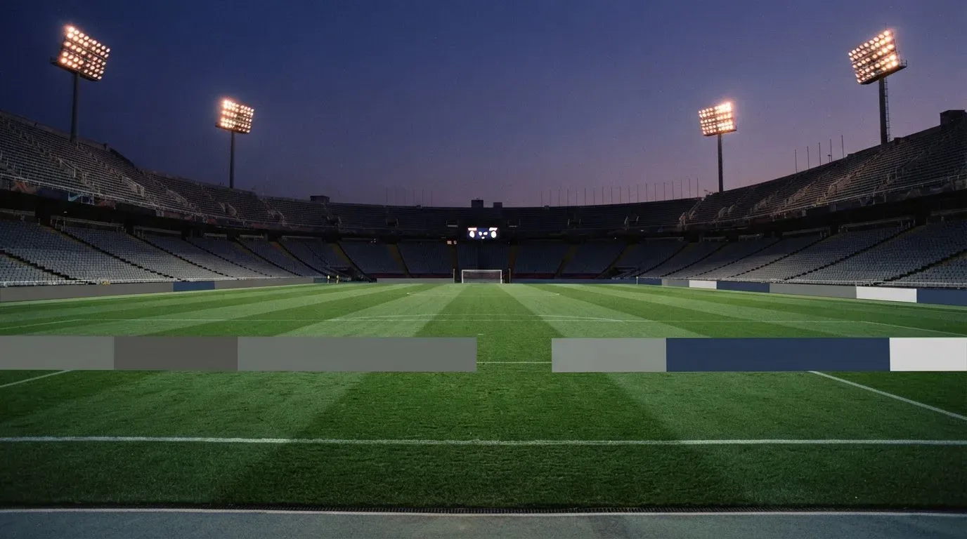An empty football stadium with floodlight masts at dusk