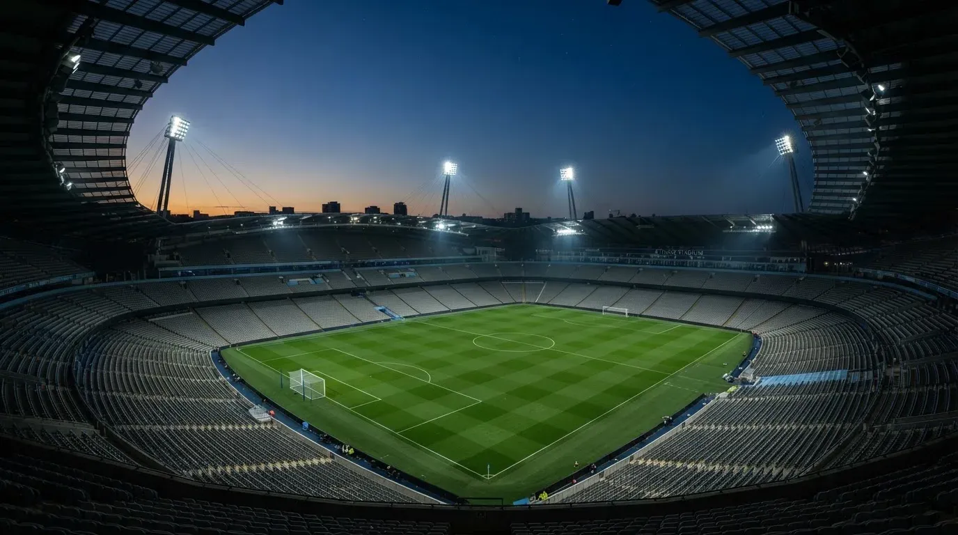 An empty football stadium with floodlight masts at dusk
