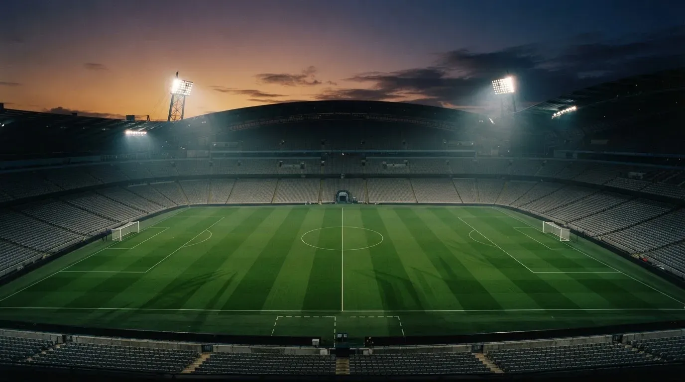 An empty football stadium with floodlight masts at dusk