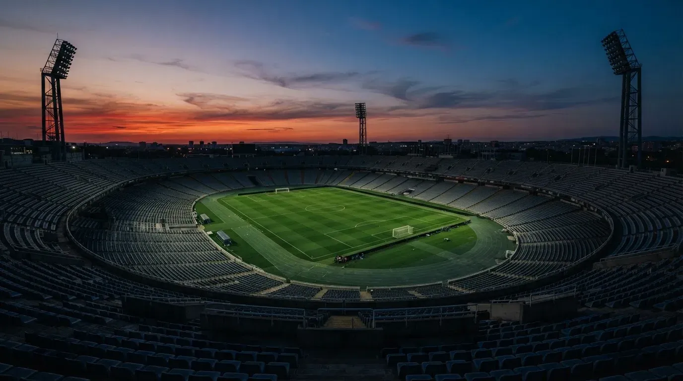 An empty football stadium with floodlight masts at dusk