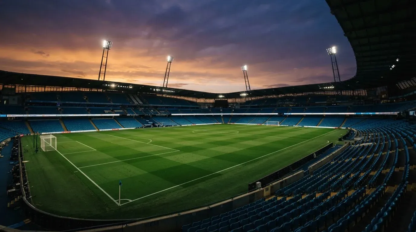 An empty football stadium with floodlight masts at dusk