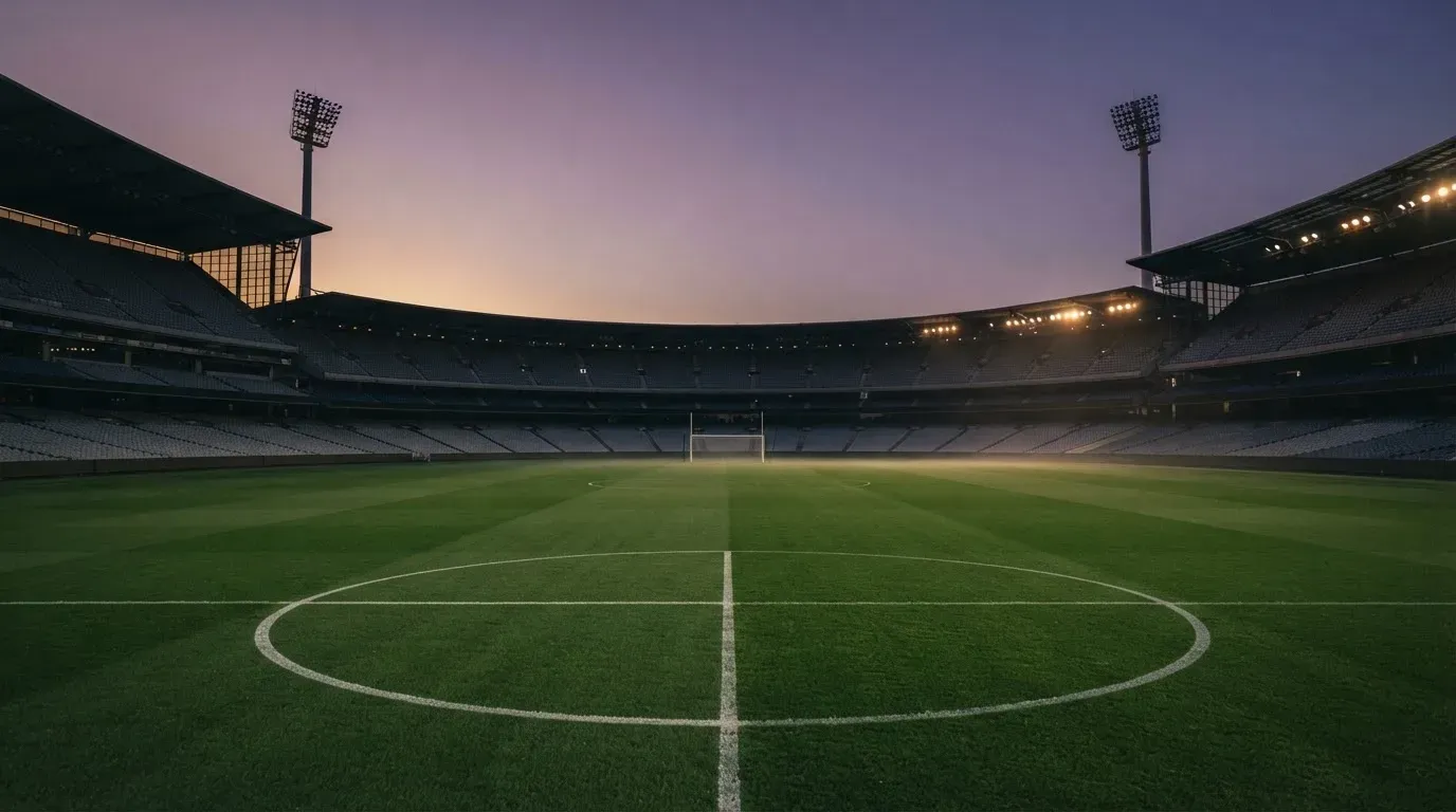 An empty football stadium with floodlight masts at dusk
