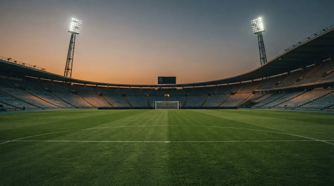 An empty football stadium with floodlight masts at dusk