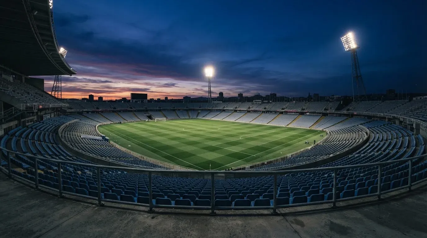 An empty football stadium with floodlight masts at dusk