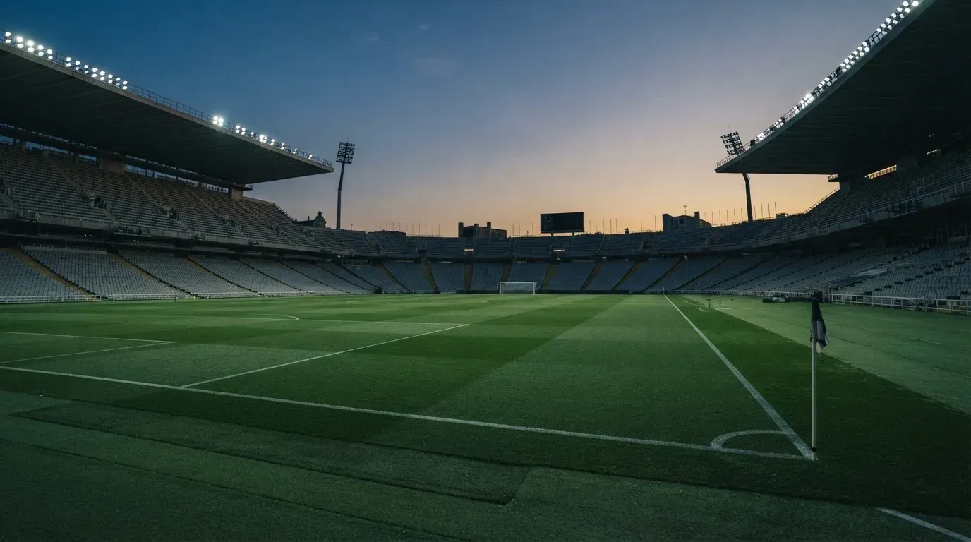 An empty football stadium with floodlight masts at dusk