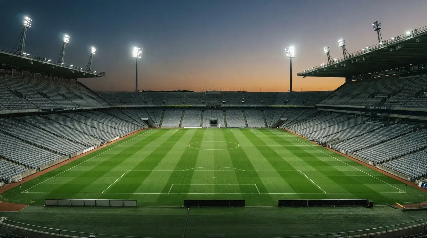 An empty football stadium with floodlight masts at dusk