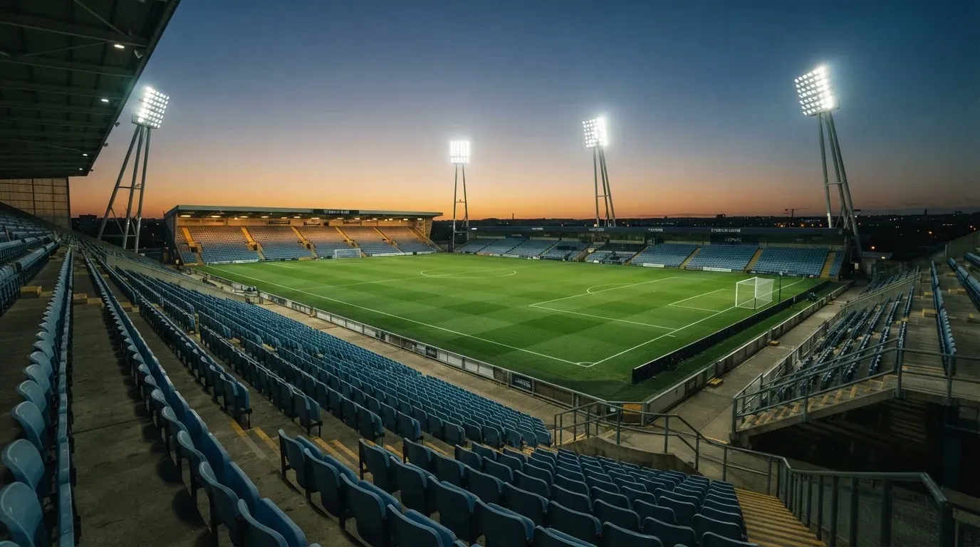An empty football stadium with floodlight masts at dusk