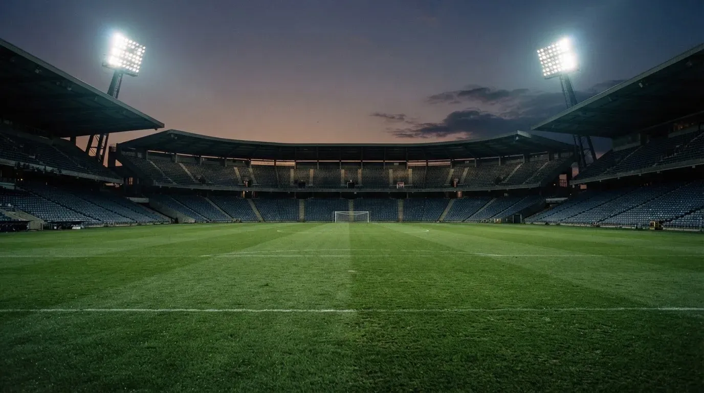 An empty football stadium with floodlight masts at dusk