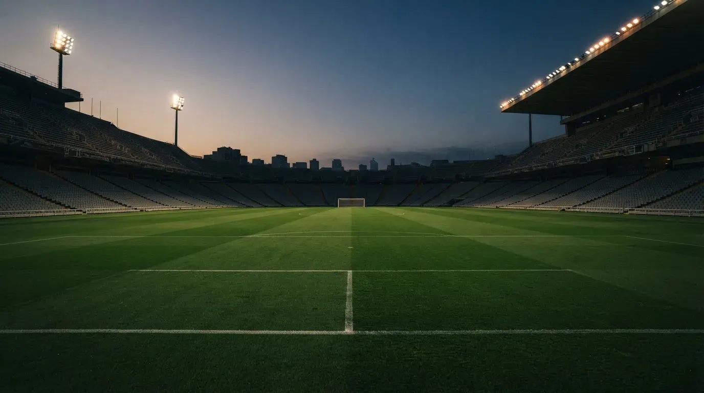 An empty football stadium with floodlight masts at dusk