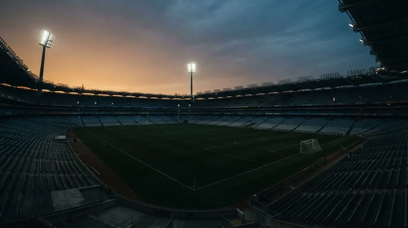 An empty football stadium with floodlight masts at dusk
