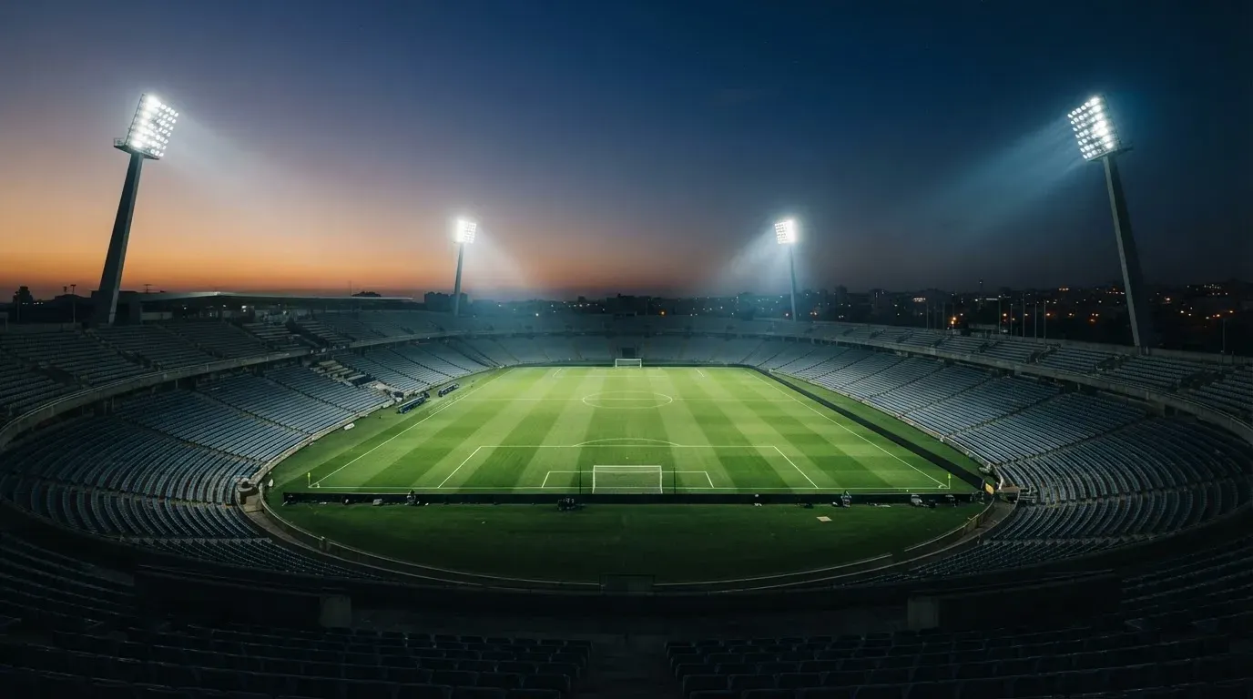 An empty football stadium with floodlight masts at dusk