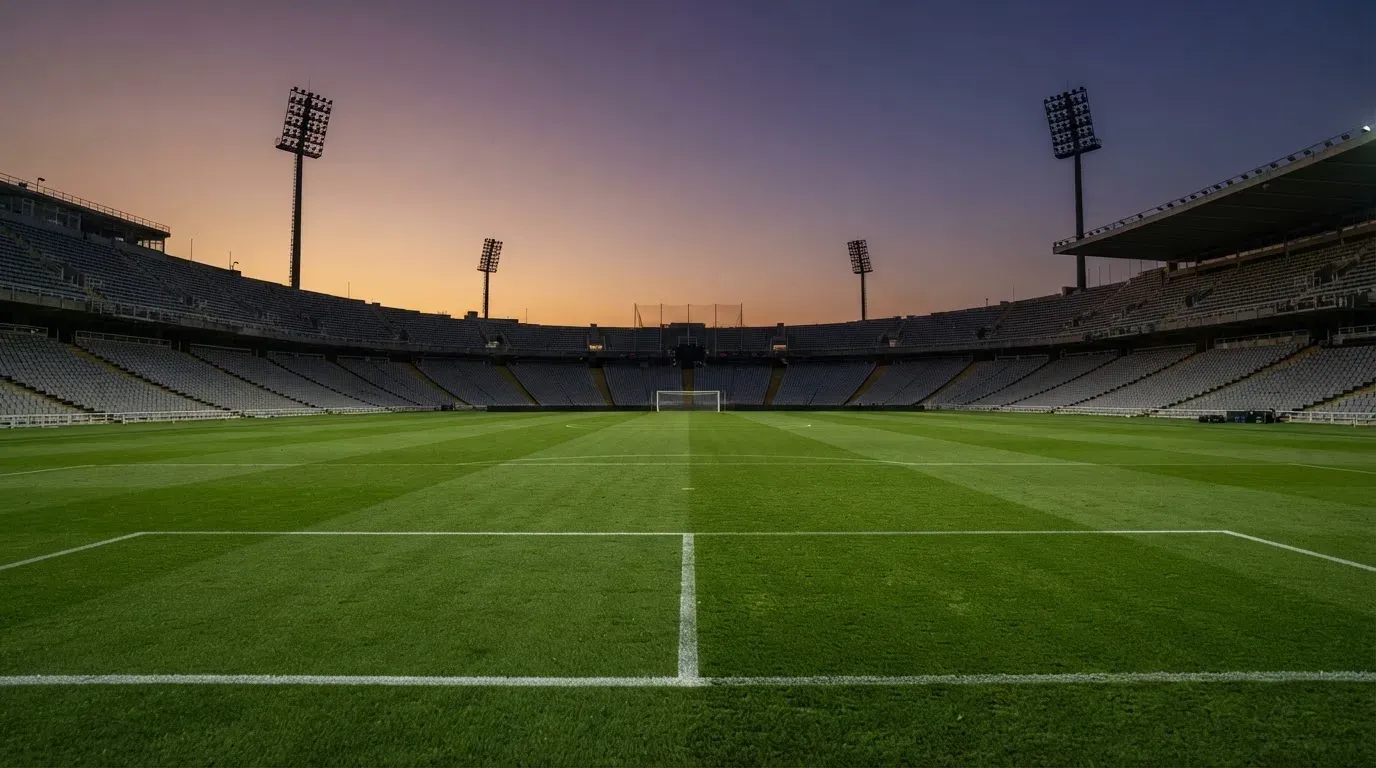 An empty football stadium with floodlight masts at dusk