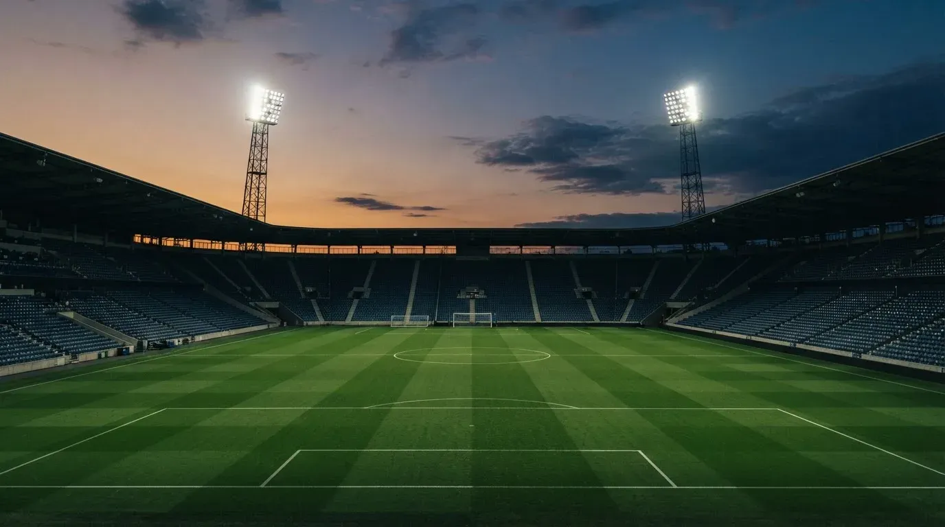 An empty football stadium with floodlight masts at dusk