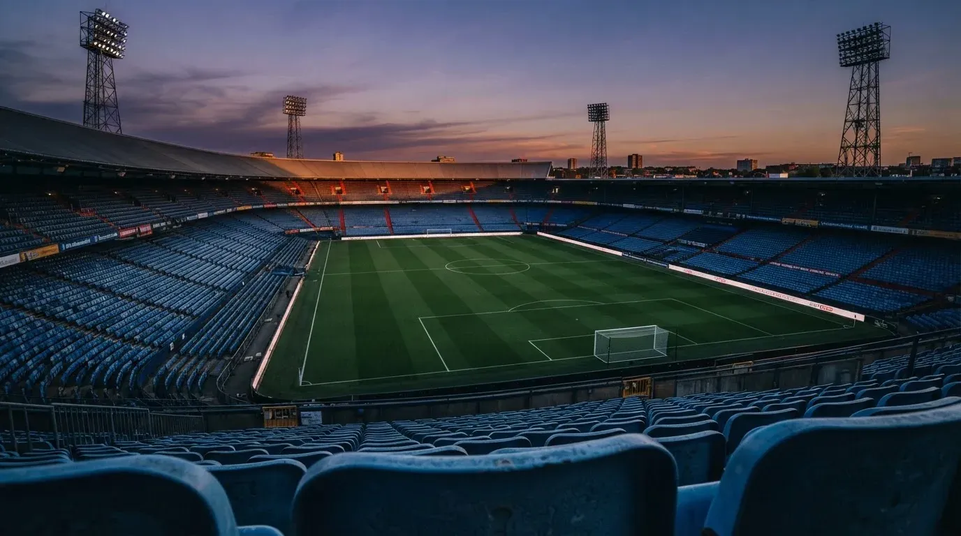 An empty football stadium with floodlight masts at dusk