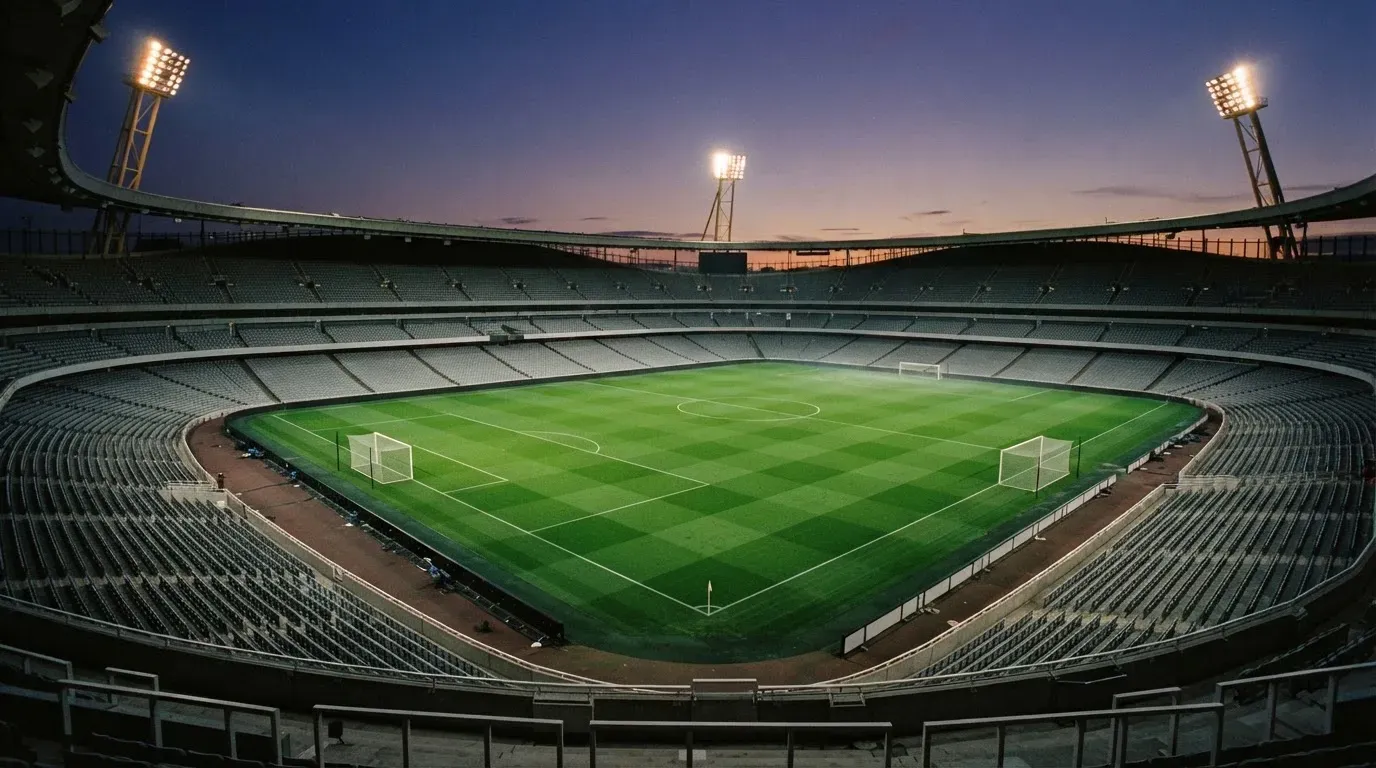 An empty football stadium with floodlight masts at dusk