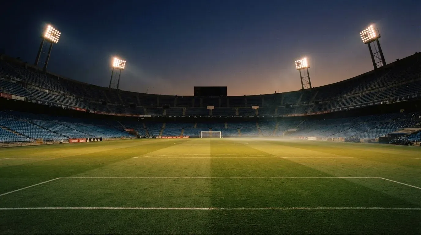 An empty football stadium with floodlight masts at dusk