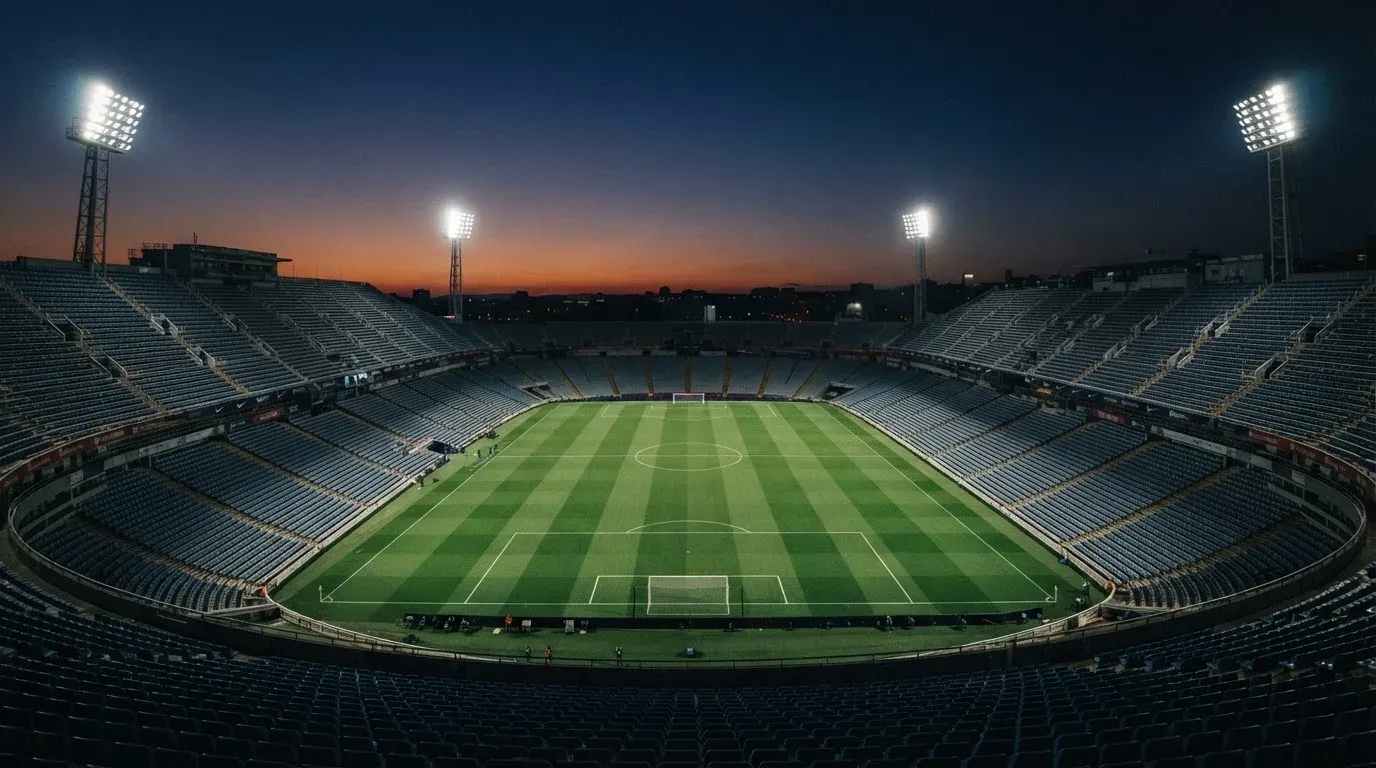 An empty football stadium with floodlight masts at dusk