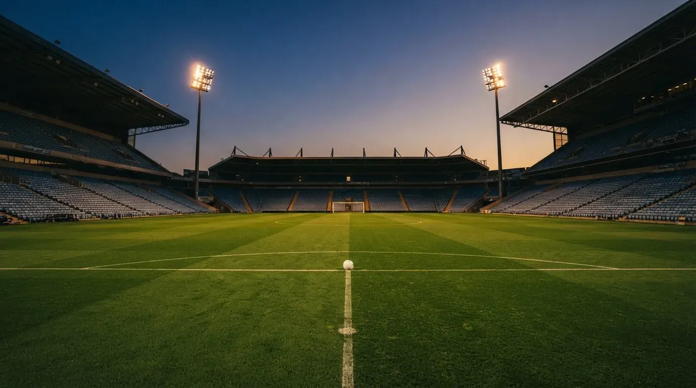 An empty football stadium with floodlight masts at dusk