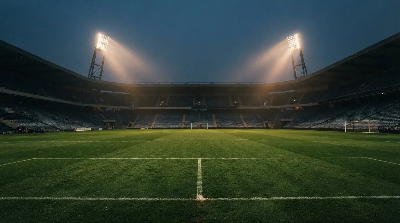 An empty football stadium with floodlight masts at dusk