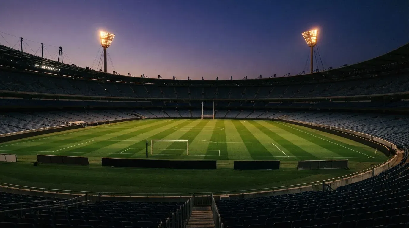 An empty football stadium with floodlight masts at dusk