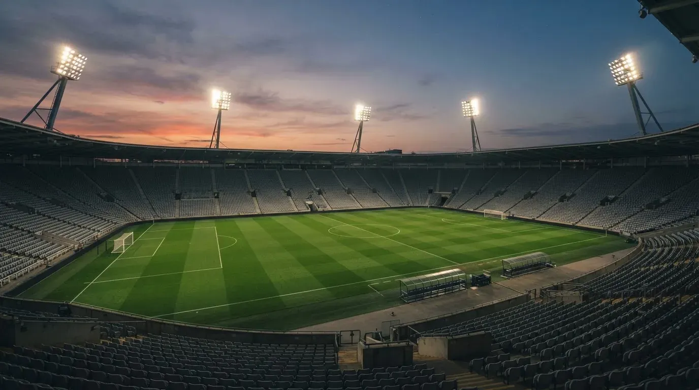 An empty football stadium with floodlight masts at dusk