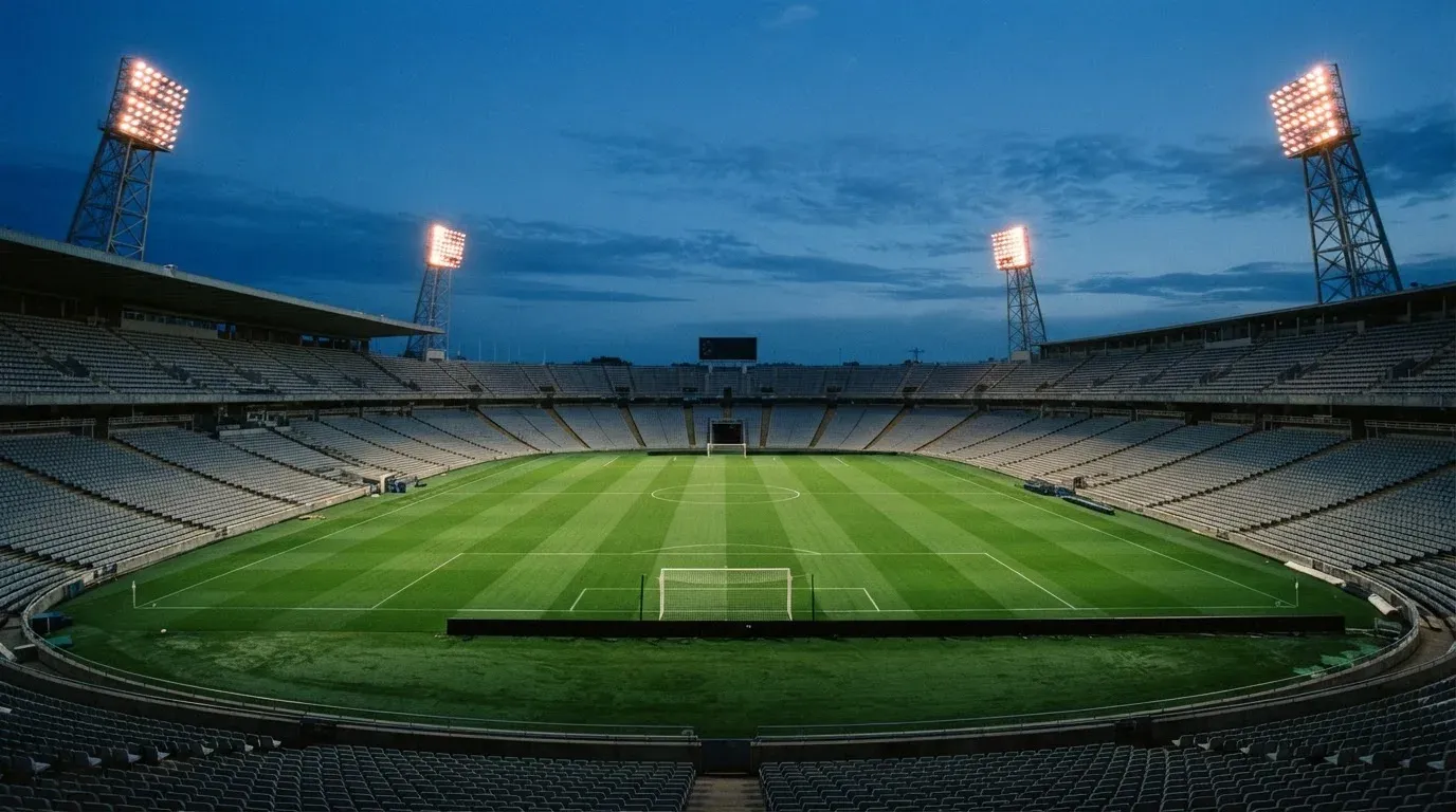 An empty football stadium with floodlight masts at dusk