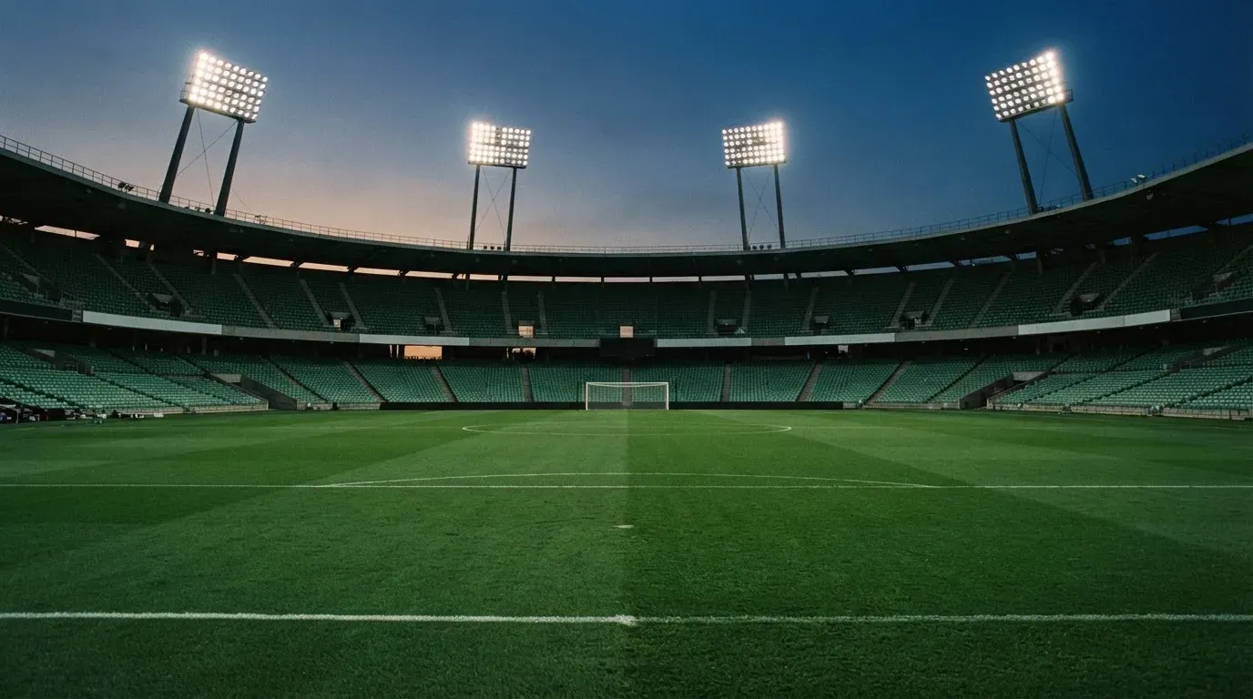 An empty football stadium with floodlight masts at dusk