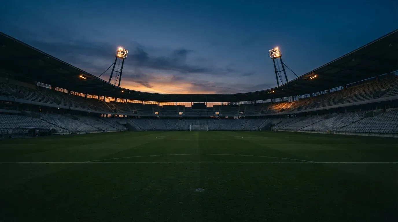 An empty football stadium with floodlight masts at dusk
