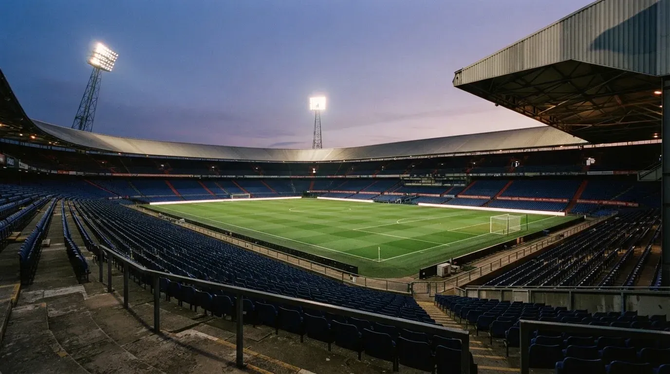 An empty football stadium with floodlight masts at dusk