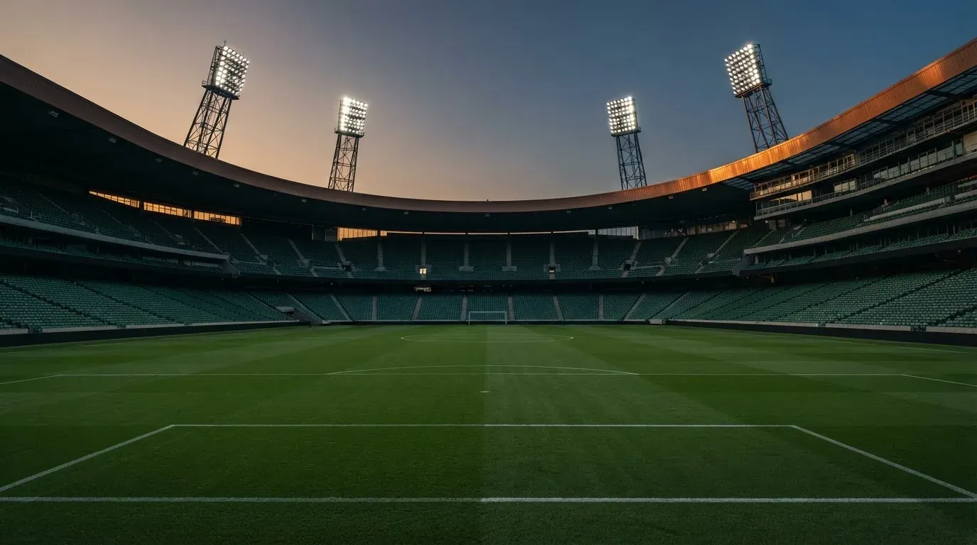 An empty football stadium with floodlight masts at dusk