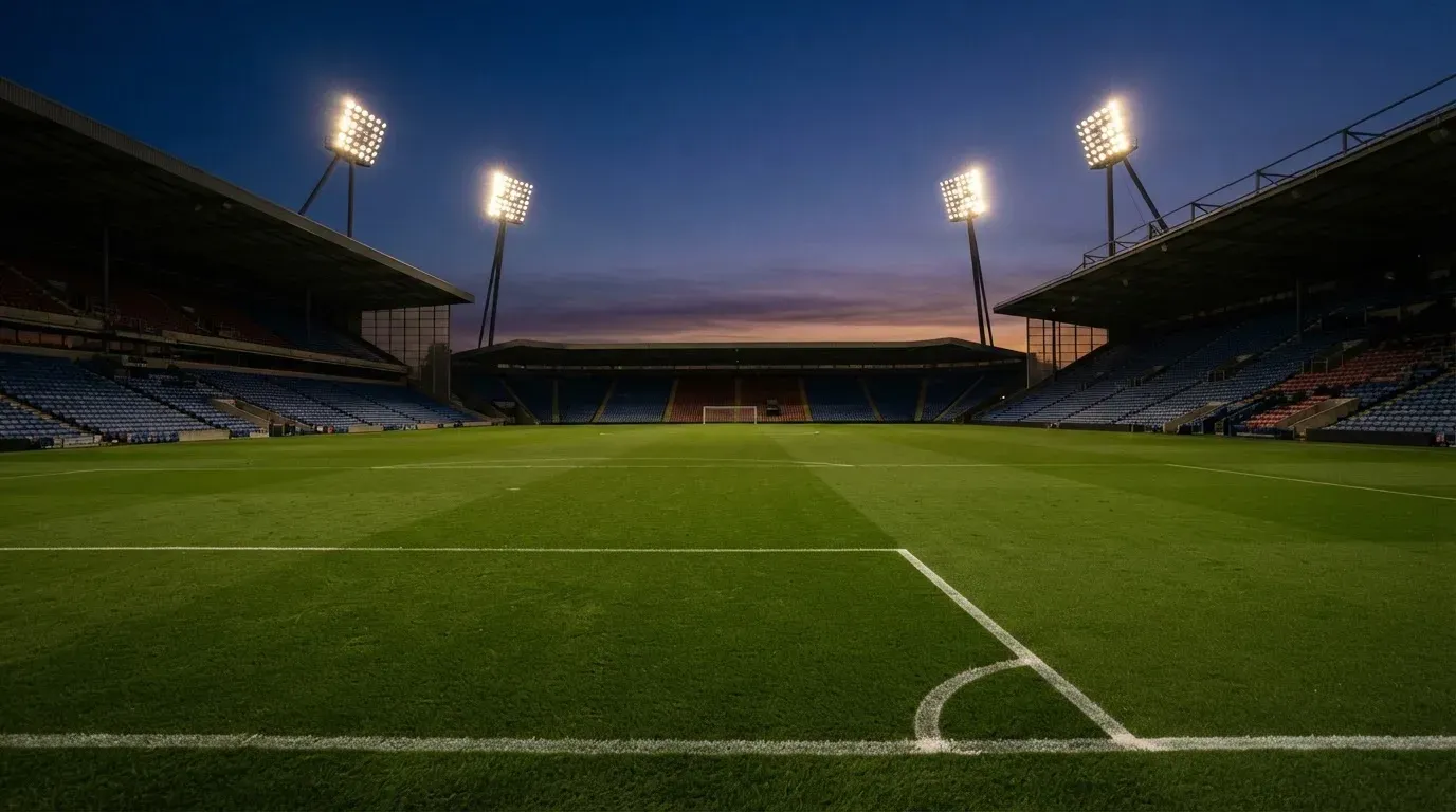 An empty football stadium with floodlight masts at dusk