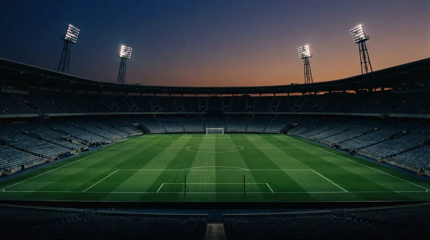 An empty football stadium with floodlight masts at dusk