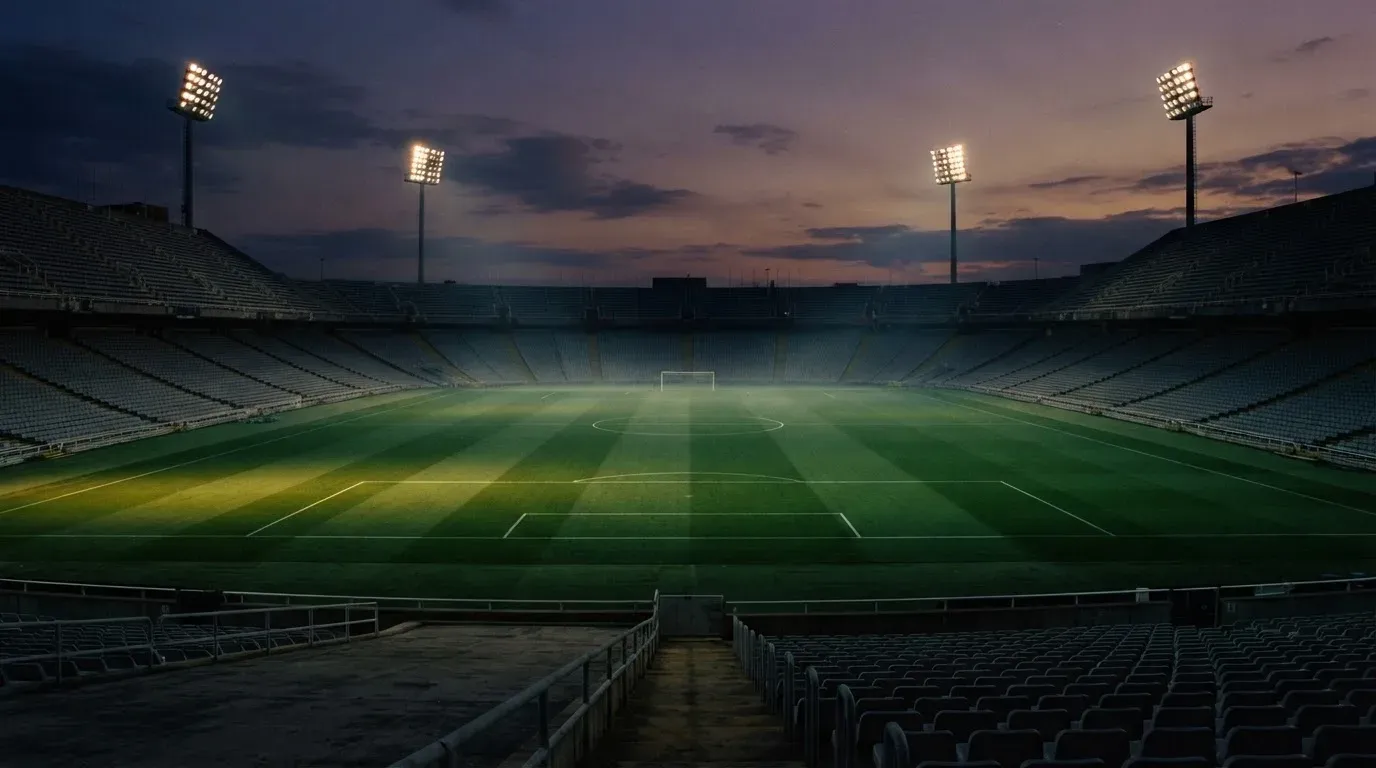 An empty football stadium with floodlight masts at dusk