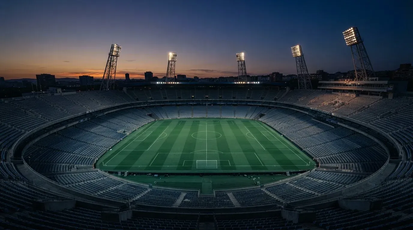 An empty football stadium with floodlight masts at dusk