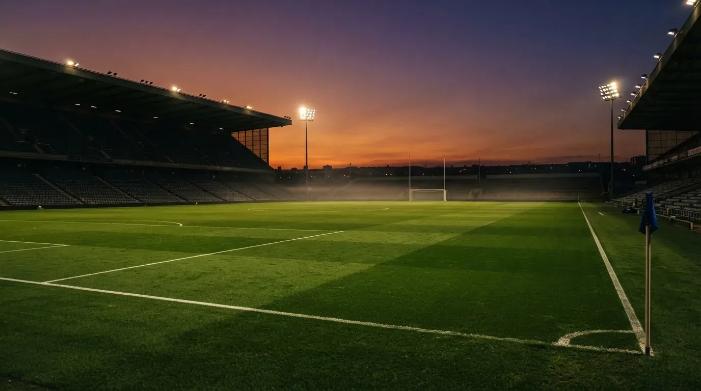 An empty football stadium with floodlight masts at dusk