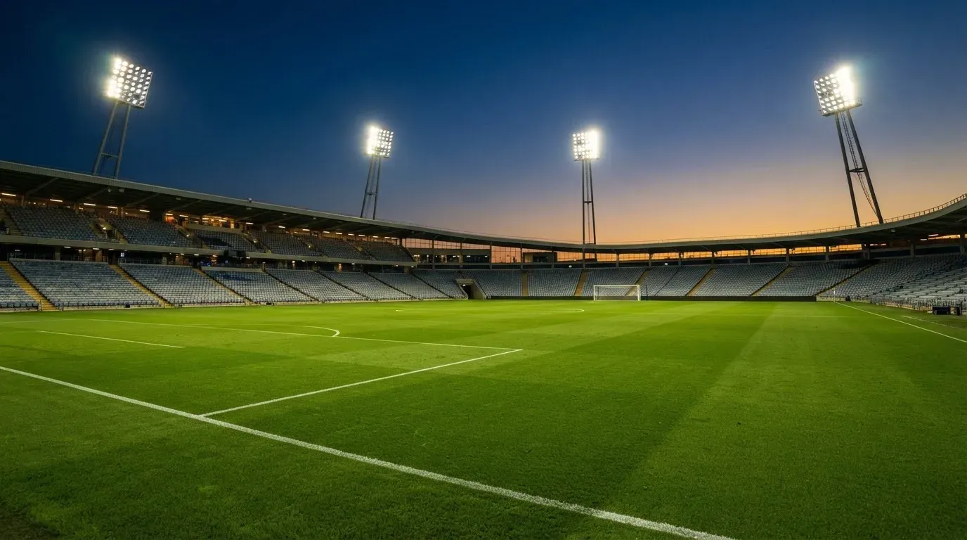 An empty football stadium with floodlight masts at dusk